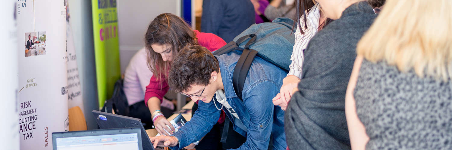 Students using a laptop at a busy recruitment fair, QMU campus, Edinburgh