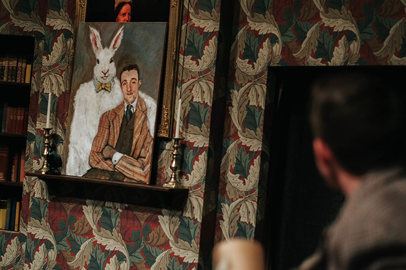 A portrait painting of a man beside a giant rabbit on retro wallpaper