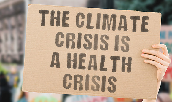 Photo of someone holding up placard that reads - The climate crisis is a health crisis
