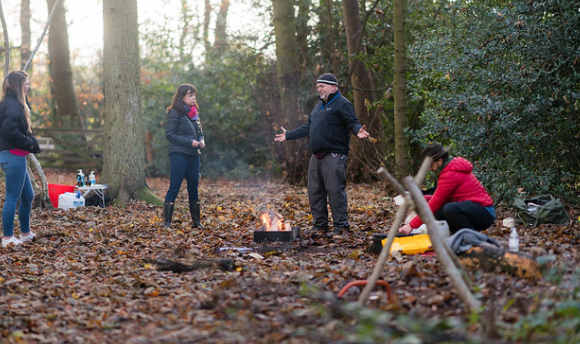 Home Economics students enjoying an outdoor learning session in a small woodland clearing, learning to carve wood and make fire.