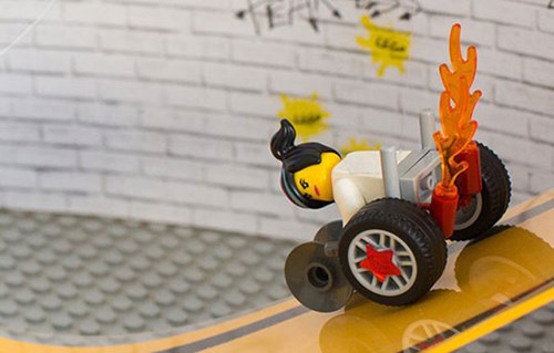 Lego character in a modern wheelchair with stars on the wheels and flames the exterior