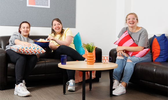 Three female students enjoy popcorn while watching a film in their QMU Student Accommodation