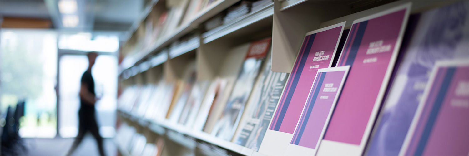 A close up shot of a bookshelf in the library filled with assorted magazines and booklets.
