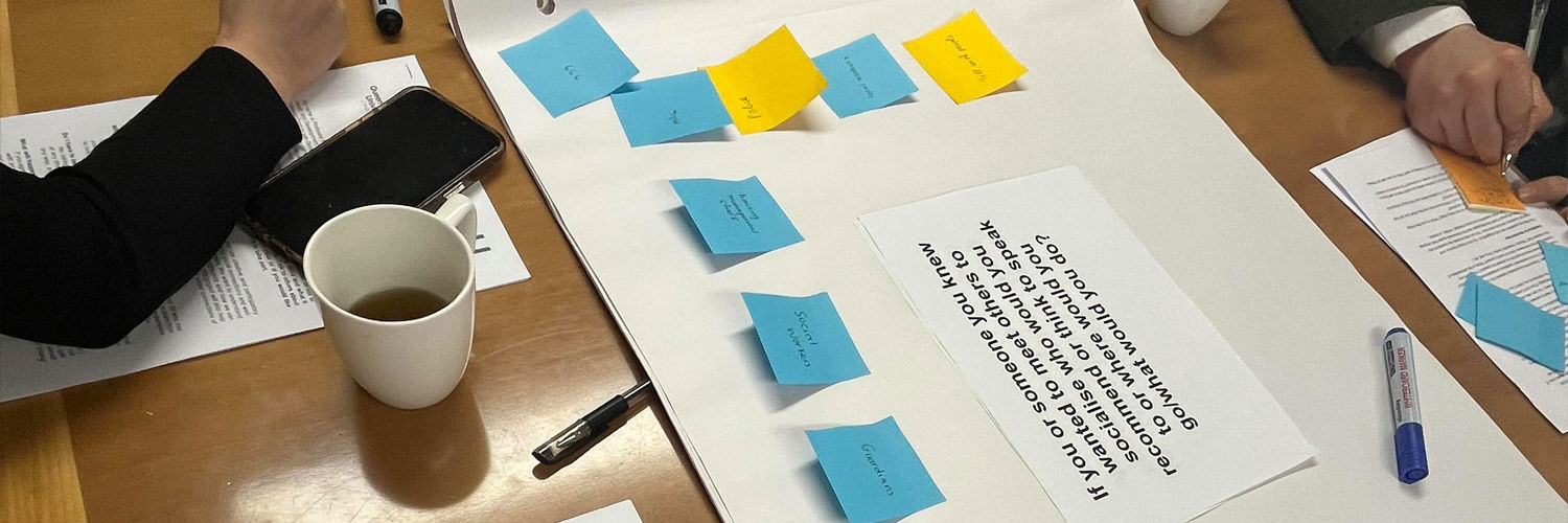 Students working together at a table, attaching sticky notes to an exercise about socialisation.
