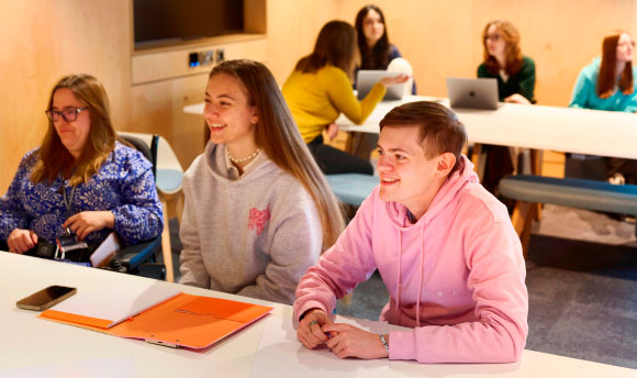 Students smiling while working in the library