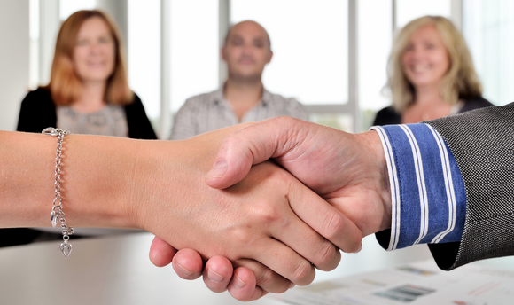 Two people shaking hands in a board room