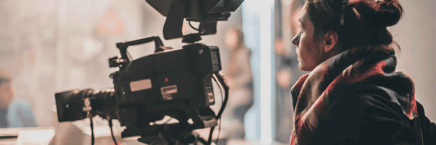 A young woman operates a large film camera.