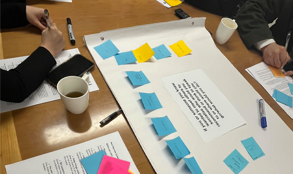 Students working together at a table, attaching sticky notes to an exercise about socialisation.