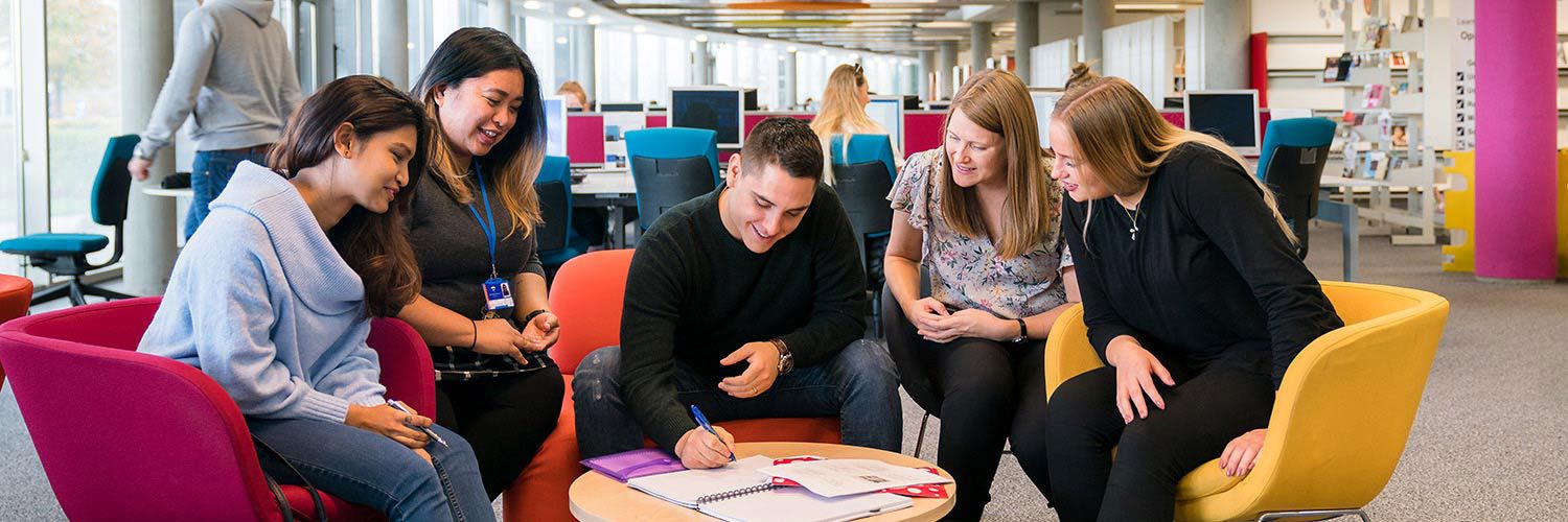 Group of strategic communication and PR students sitting round a small table and making notes