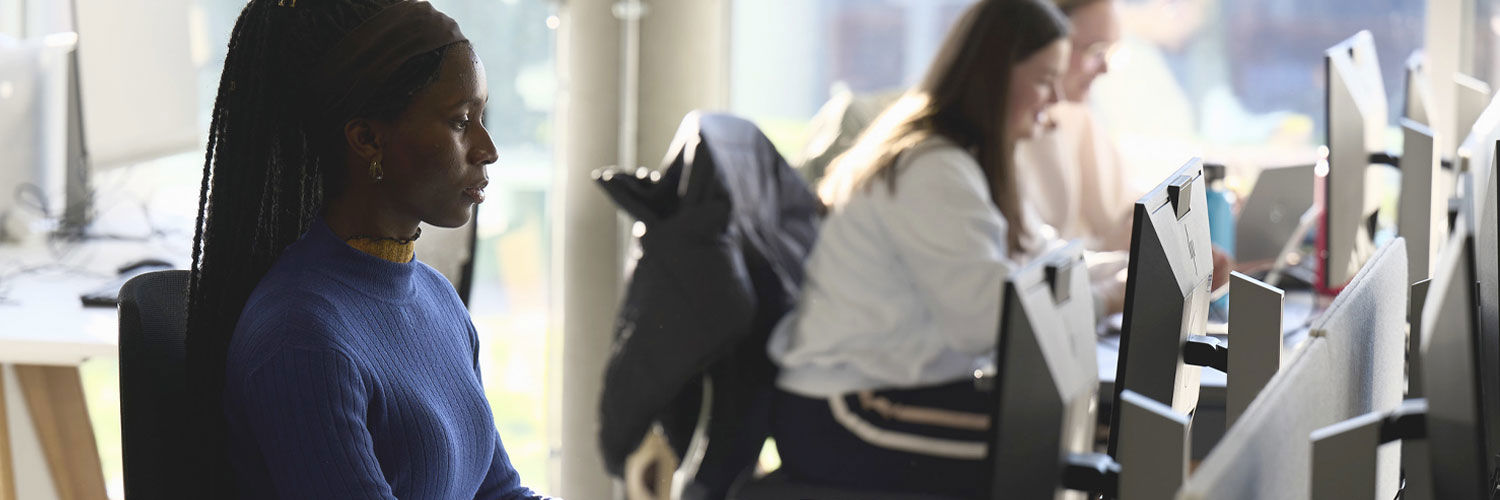 A female student sits at a computer in the library.