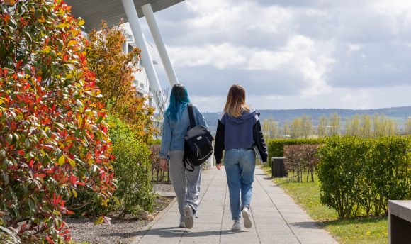 Two people walking together on the QMU campus