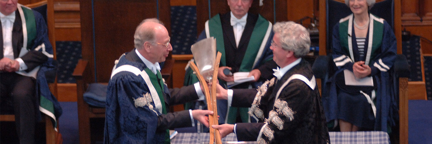 The University Mace being passed between two people at the QMU inauguration in 2007