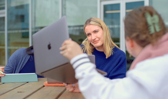 two female students working on laptops outdoors