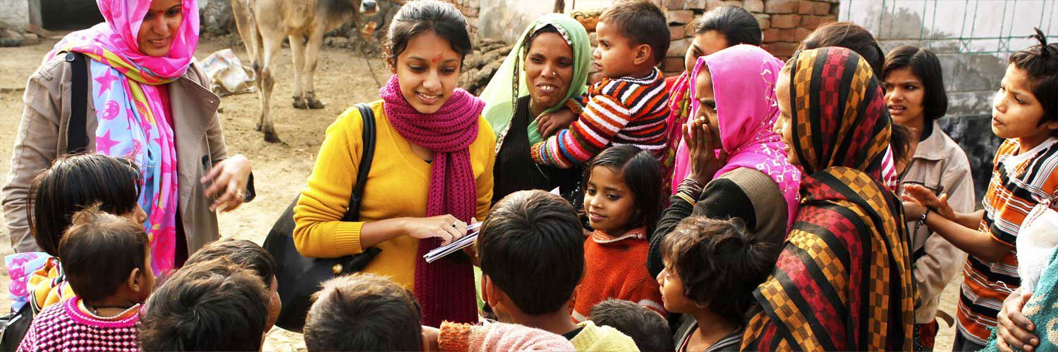 A couple of aid workers surrounded by a group of children