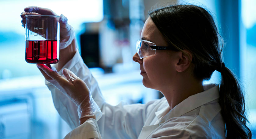 Image of a scientist looking at a liquid in a beaker