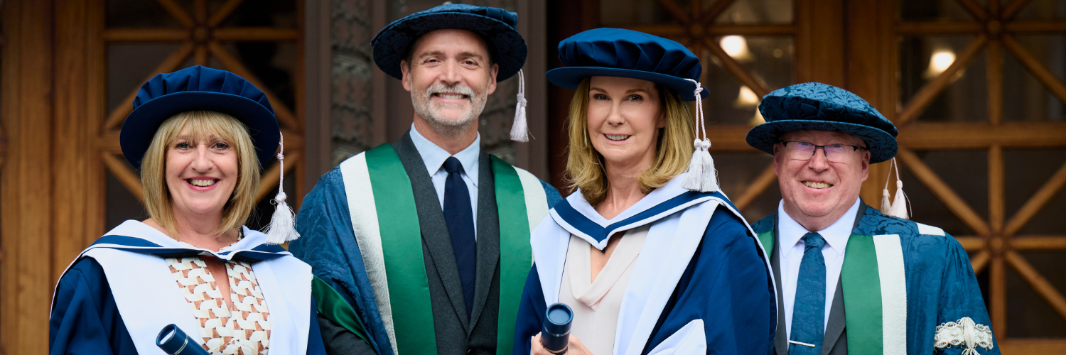 Two women and two men in ceremonial graduation gowns in front of the Usher Hall in Edinburgh