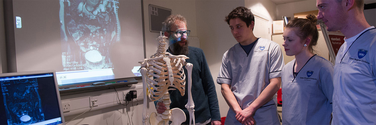 Radiography students with their lecturer looking at a model skeleton