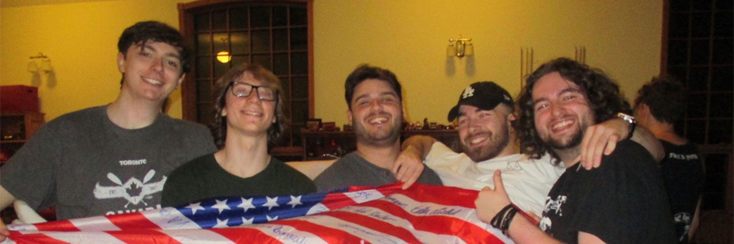 Four students holding another one up lengthways that is draped in a flag of the USA.