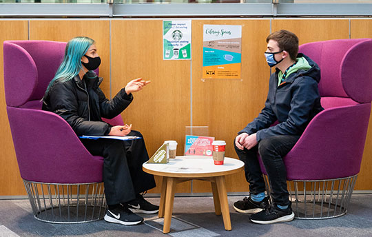 A Queen Margaret University student giving chatting with another student