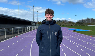 Head and shoulders image of young man with backdrop of athletics track