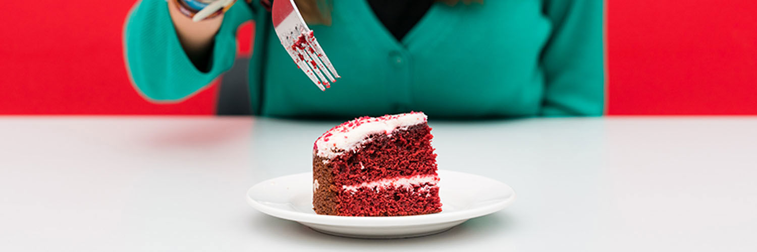 A person about to dig into a slice of red velvet cake