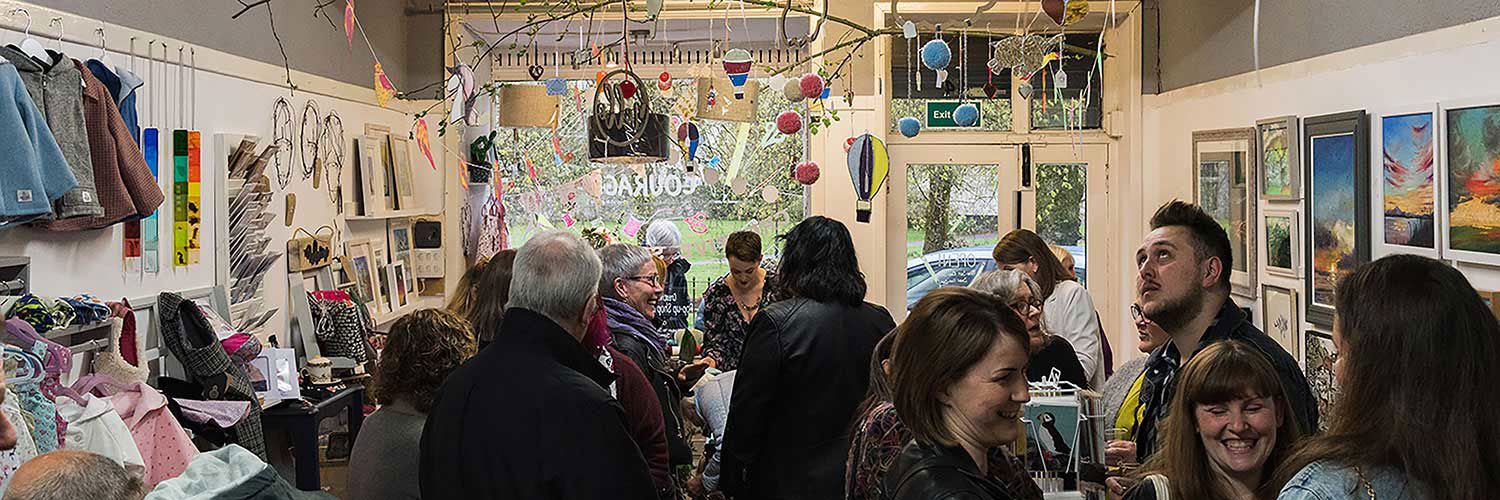 A busy store with art lining the walls and small decorations suspended from the roof