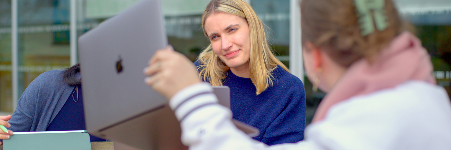 two female students working on laptops outdoors