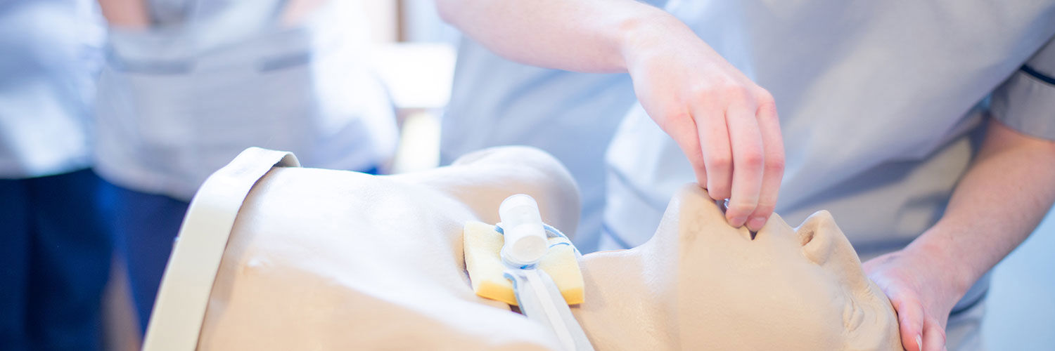 A student nurse practicing unblocking the airways on a resuscitation dummy