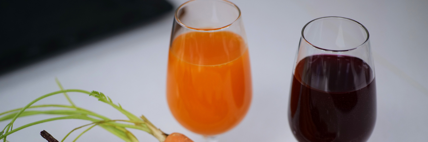 One glass with vibrant orange liquid and one glass with blackcurrant purple liquid