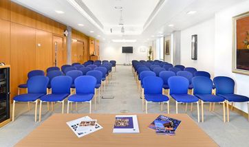 Long room with rows of blue chairs facing forward, QMU