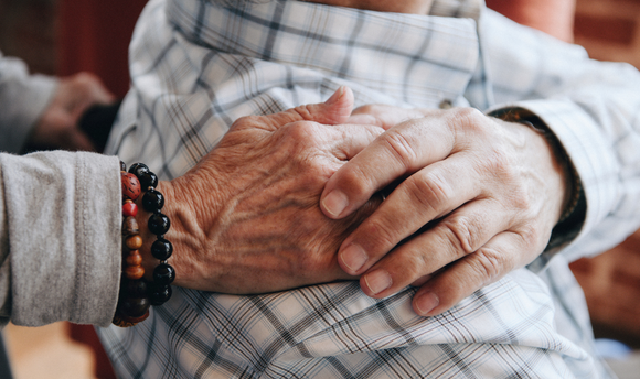 Two older people's hands touching