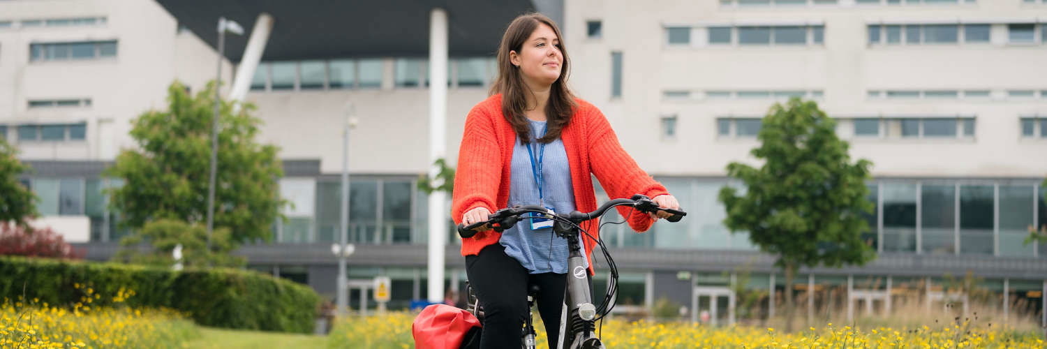 Student cycling on campus grounds