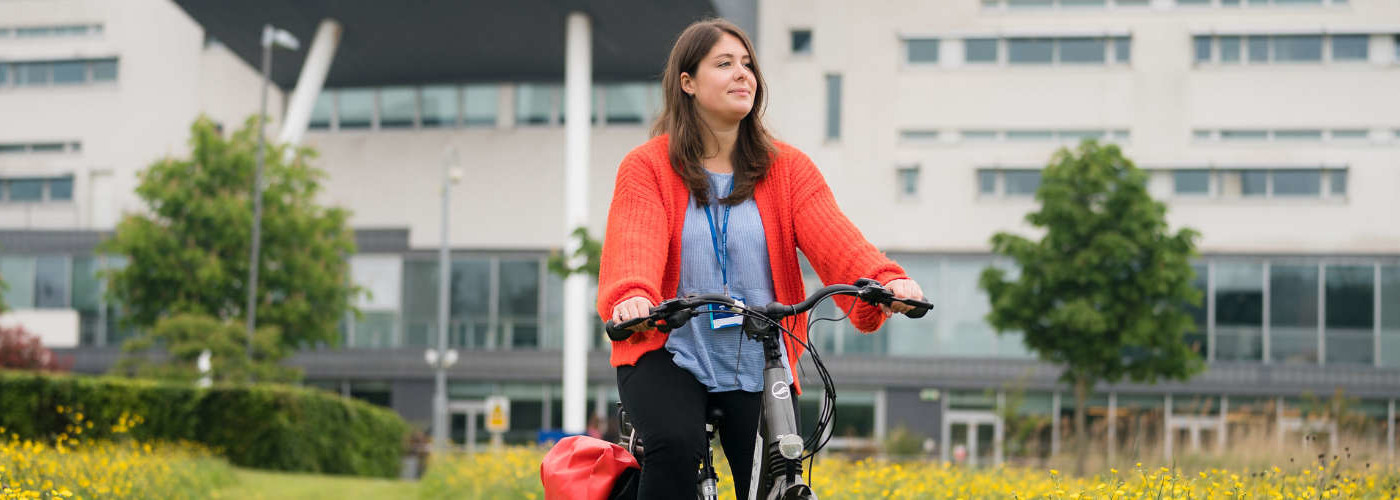 Student cycling on campus grounds