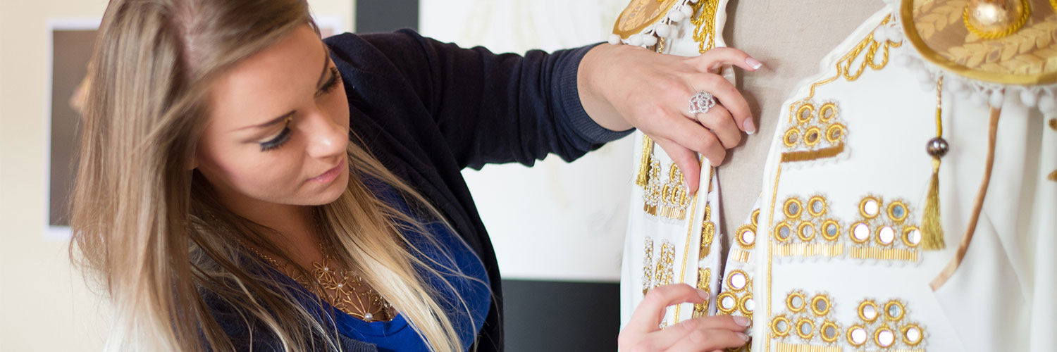 Queen Margaret University Costume Design student designing a white jacket with gold detail