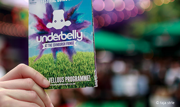 Hand holding up an Underbelly at the Edinburgh Fringe programme