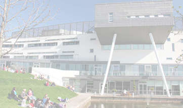 Students laying on the grass beside the fountain outside Queen Margaret University Campus