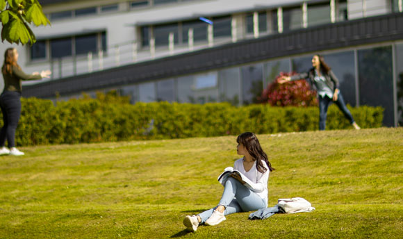 Students playing frisbee on the grass outside Queen Margaret University, Edinburgh