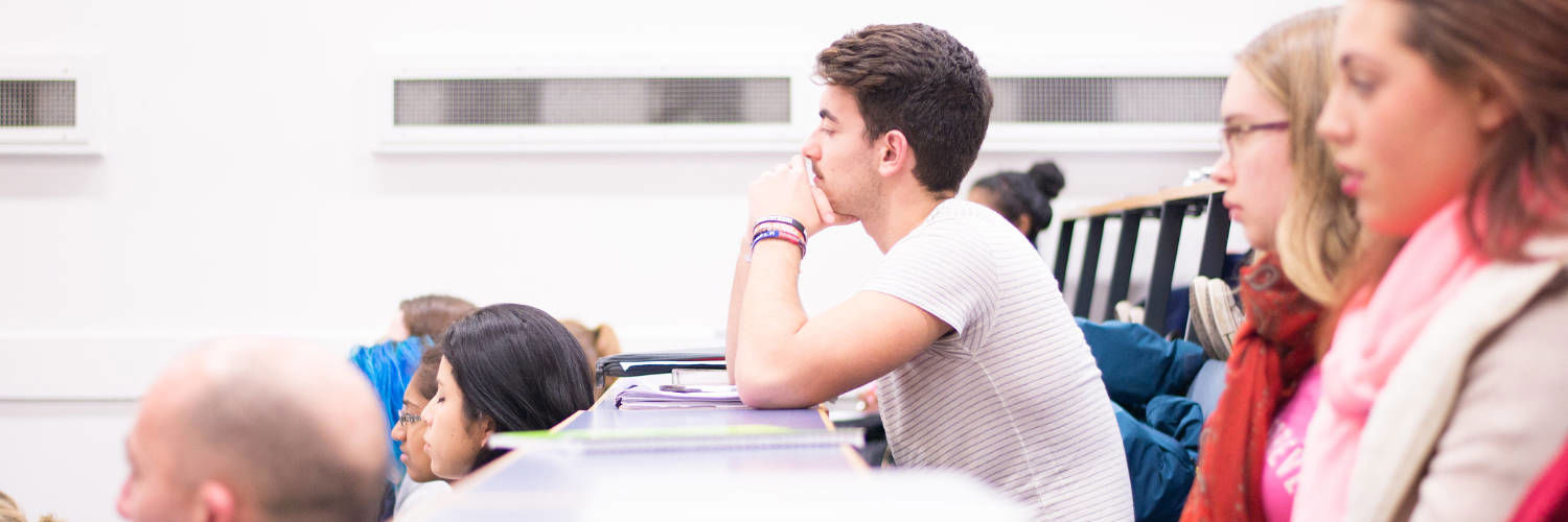 A student in a lecture theatre, listening intently