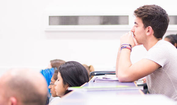 A student in a lecture theatre, listening intently