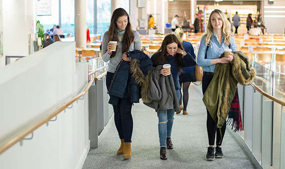 3 girls walking up an access ramp with drinks in their hands, QMU, Edinburgh