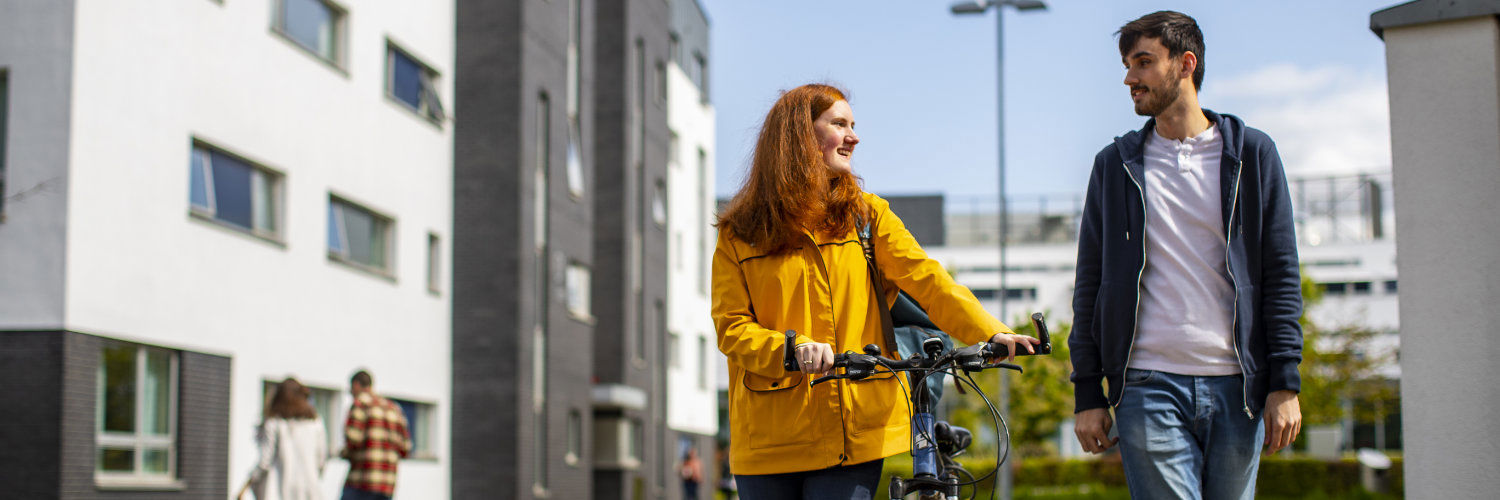 A QMU student with a bike talking to a fellow student on campus, Edinburgh