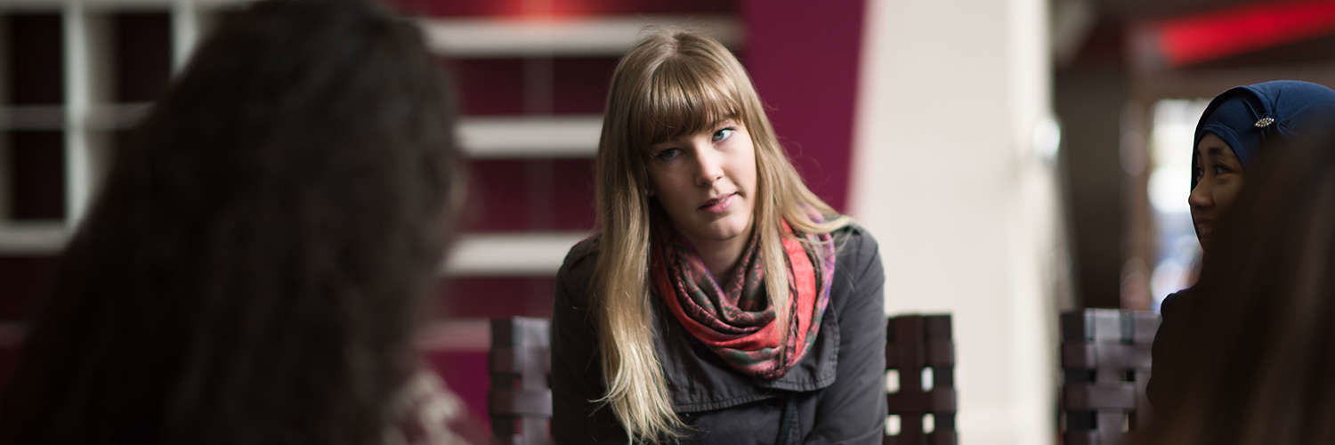 Student listening intently to her fellow student whilst another smiles on, QMU, Edinburgh