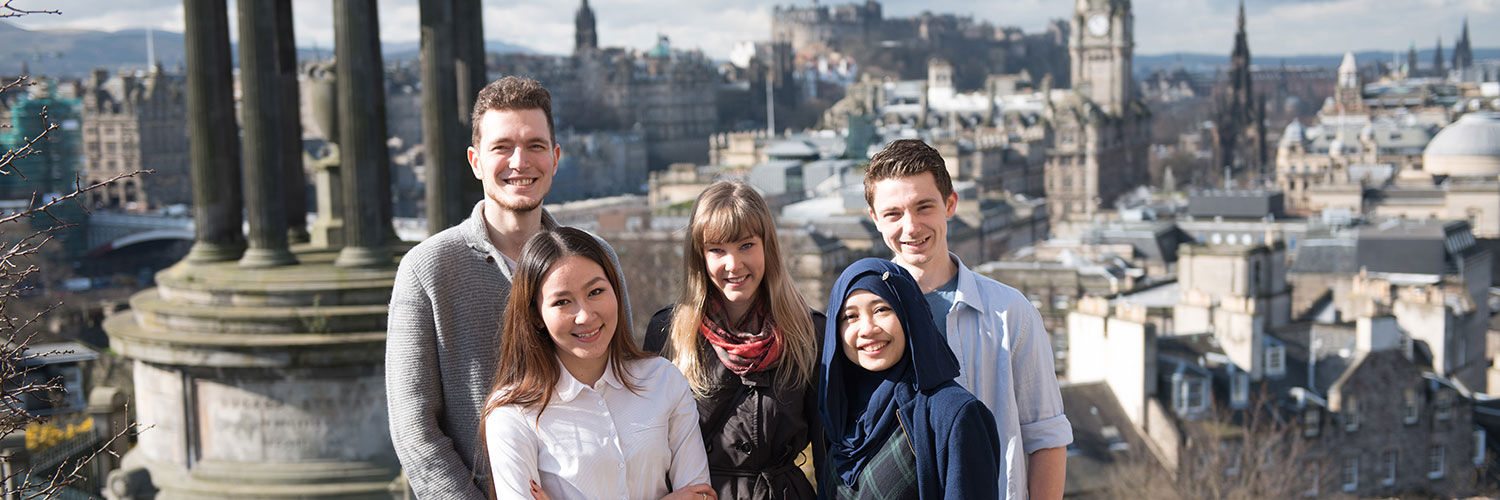 Group of students smiling in front of the Dugald Stewart Monument, Edinburgh