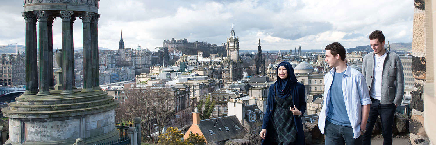 Students standing by the Dugald Stewart Monument with Edinburgh sprawling behind them
