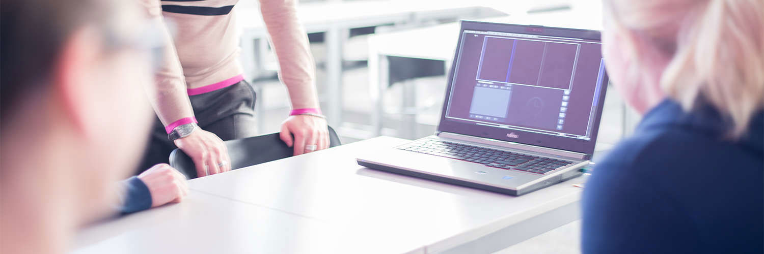 A group of students crowded round a laptop, Queen Margaret University, Edinburgh