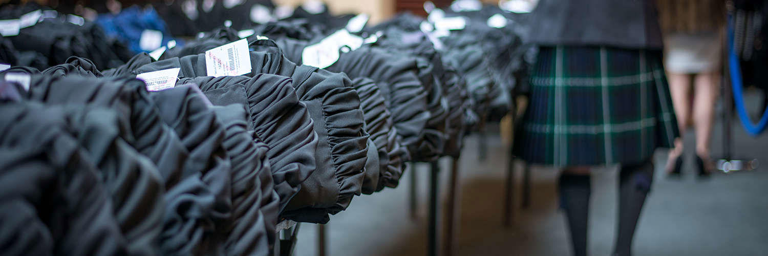 Rows of graduation gowns folded on tables