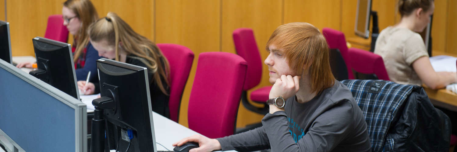A Queen Margaret University student working alone at their computer desk, Edinburgh