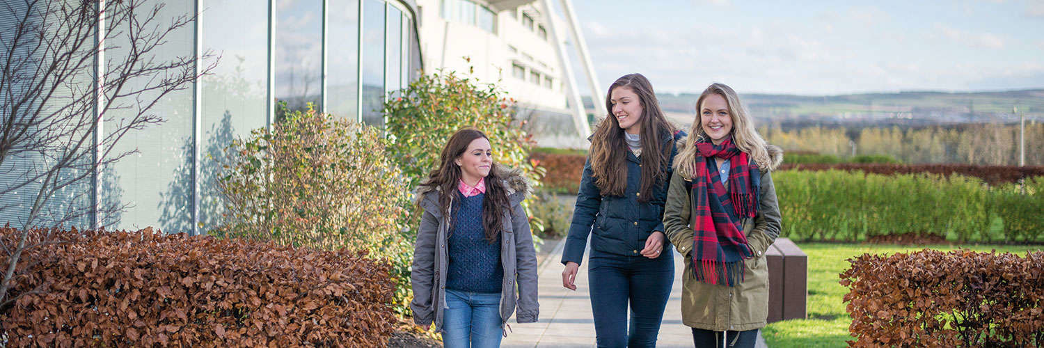 3 girls in winter jackets outside the Queen Margaret University Campus, Edinburgh