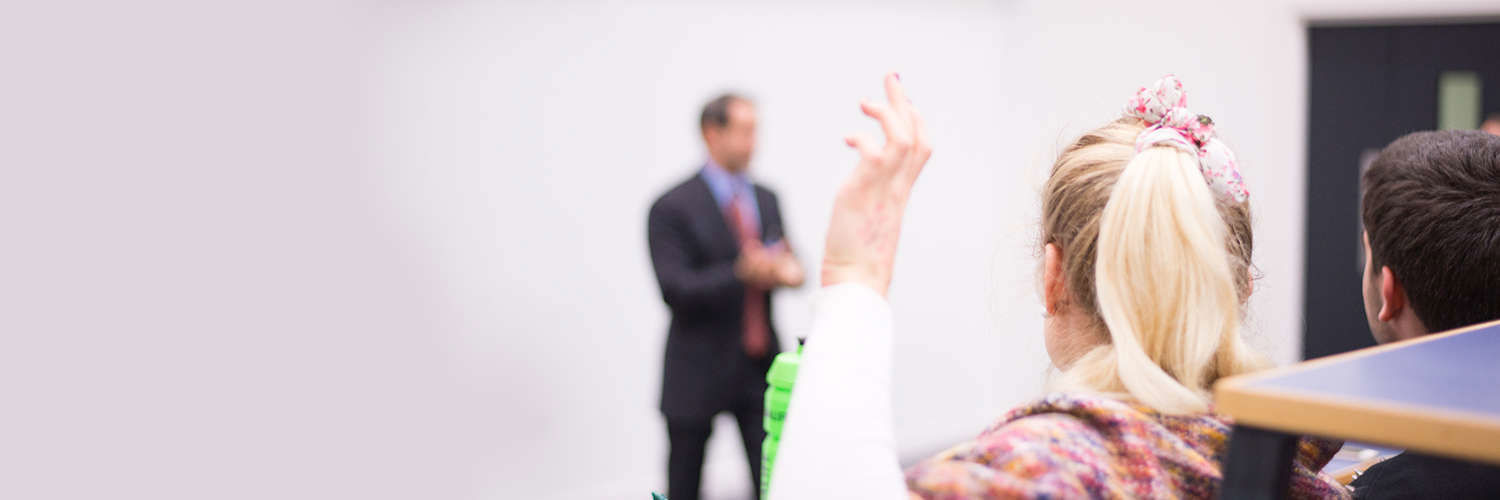 A Queen Margaret University student raising their hand with a question for the lecturer
