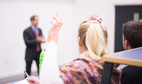 A Queen Margaret University student raising their hand with a question for the lecturer